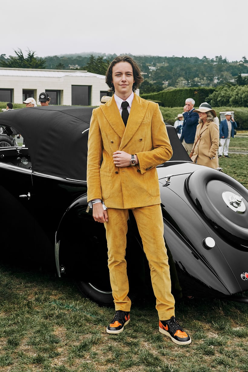 A gentleman posing in front of a vintage car.