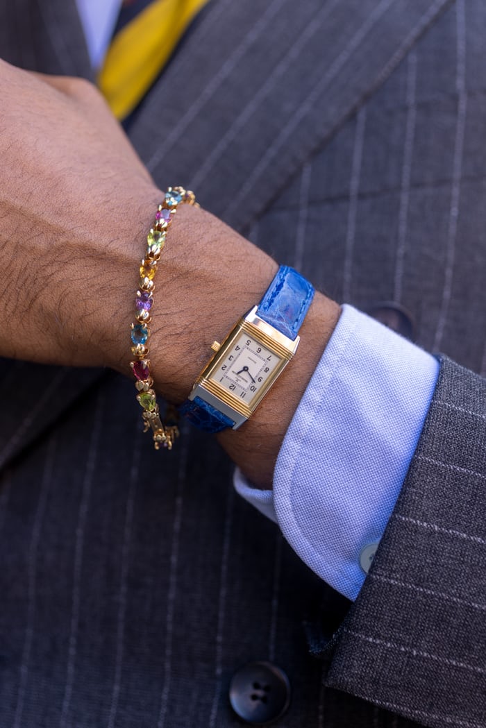Gold JLC reverso pictured on wrist with colorful crystal gold bracelt. 
