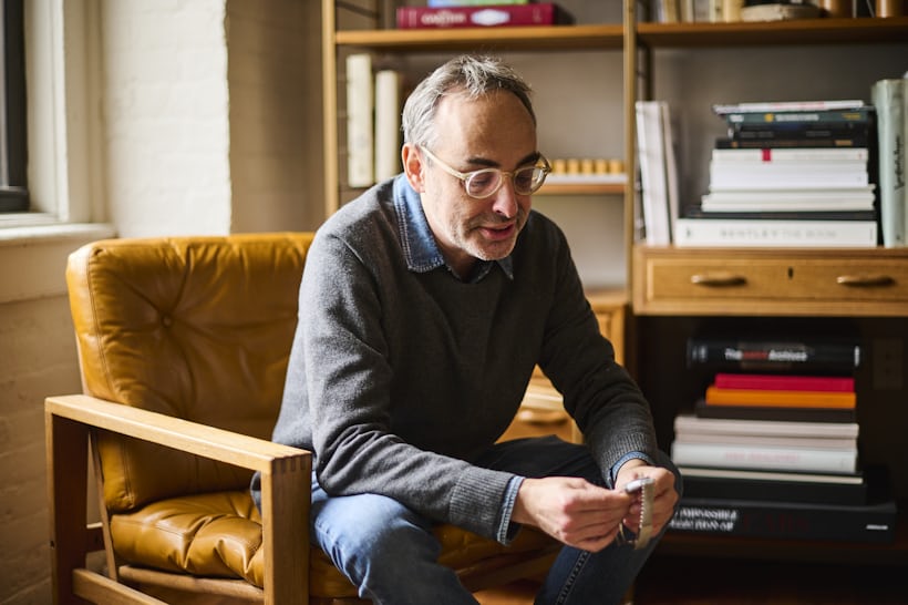 Gary Shteyngart looking at a watch while sitting in a chair