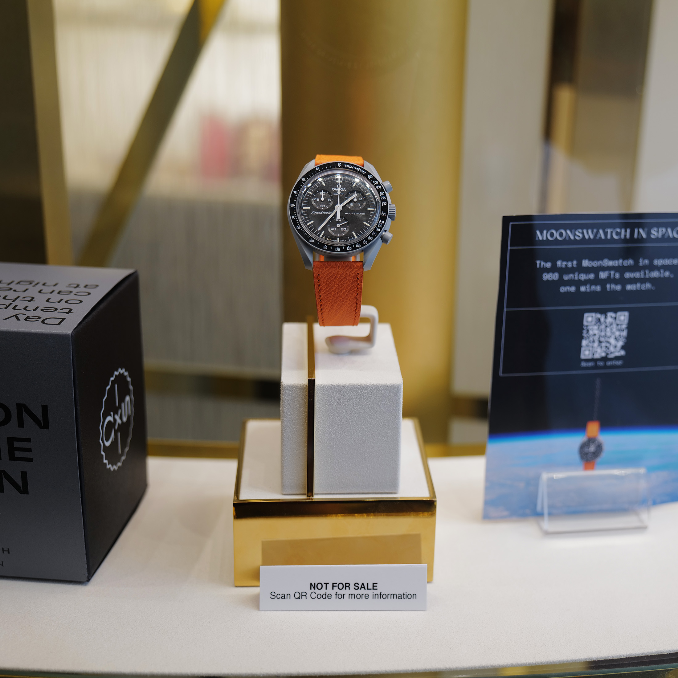 A MoonSwatch on a stand in a window display