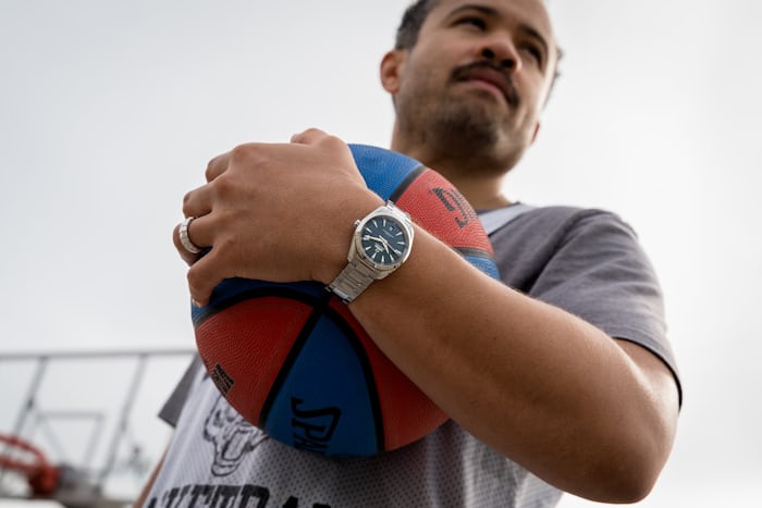 a man holding a basketball and wearing an omega watch 