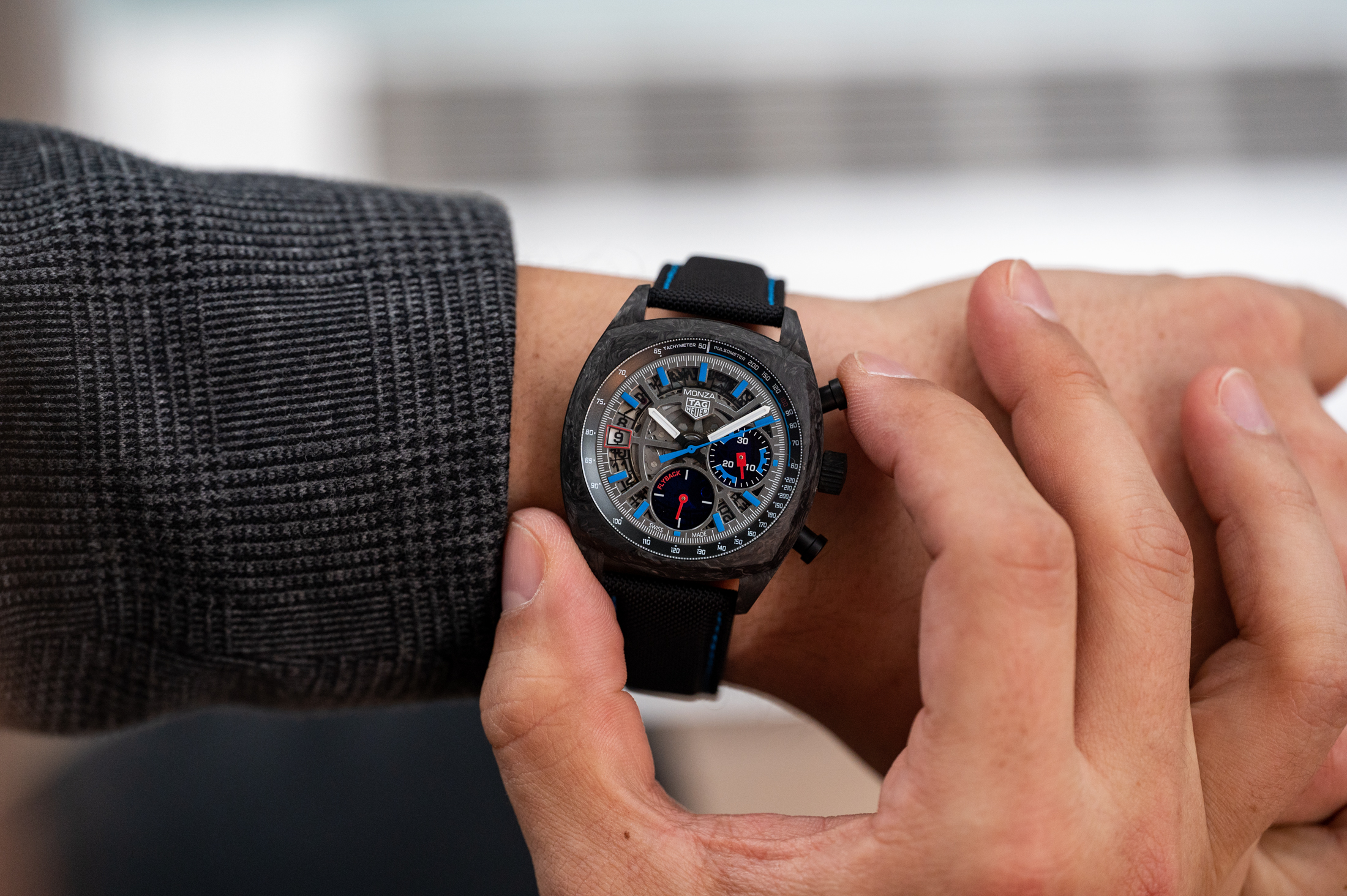 The TAG Heuer Monza skeletonized dial with a person wearing it on the wrist and pushing the pusher on the watch.