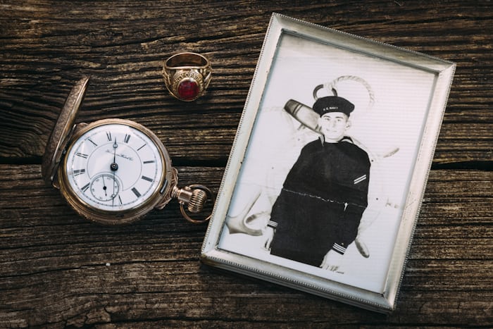 A photo of a navy sailor, a pocket watch, and class ring