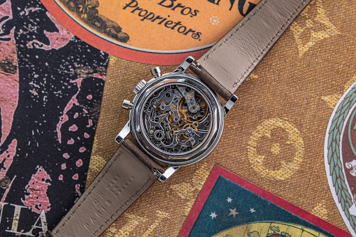 Caseback of a Patek Philippe perpetual calendar chronograph showing the visible movement on an ornate background