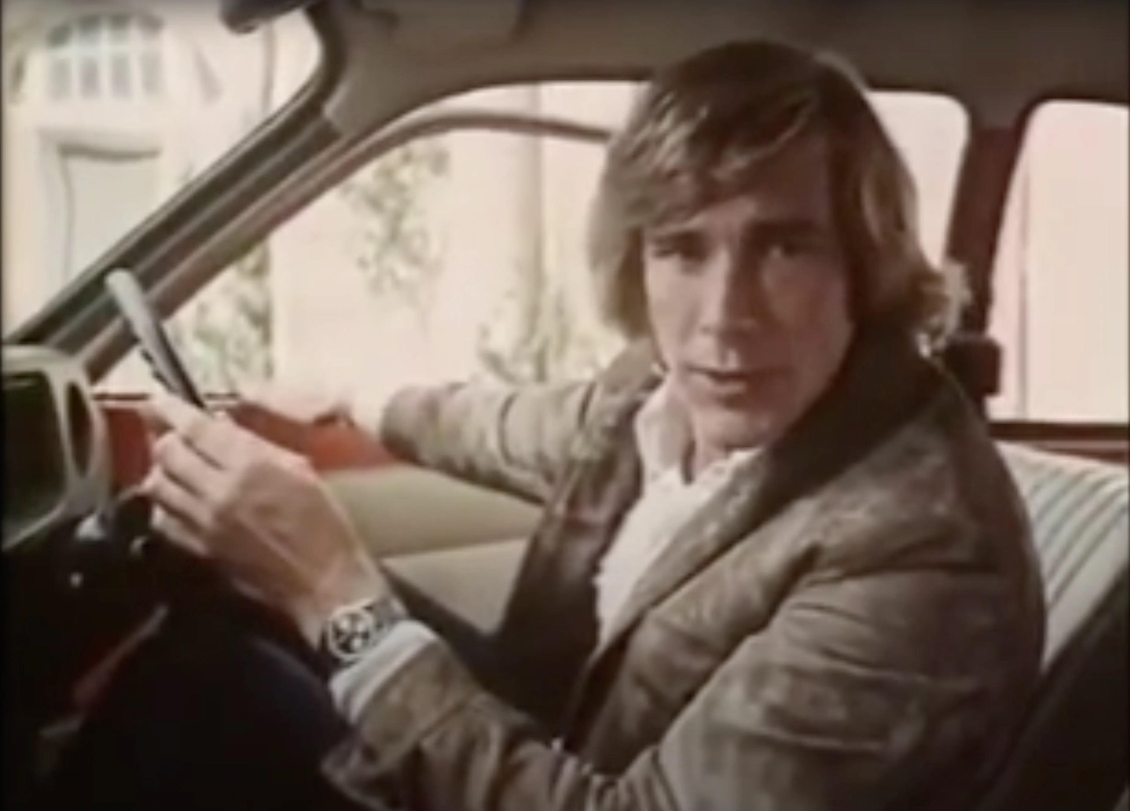 James Hunt wearing a reverse panda Carrera while sitting in a car