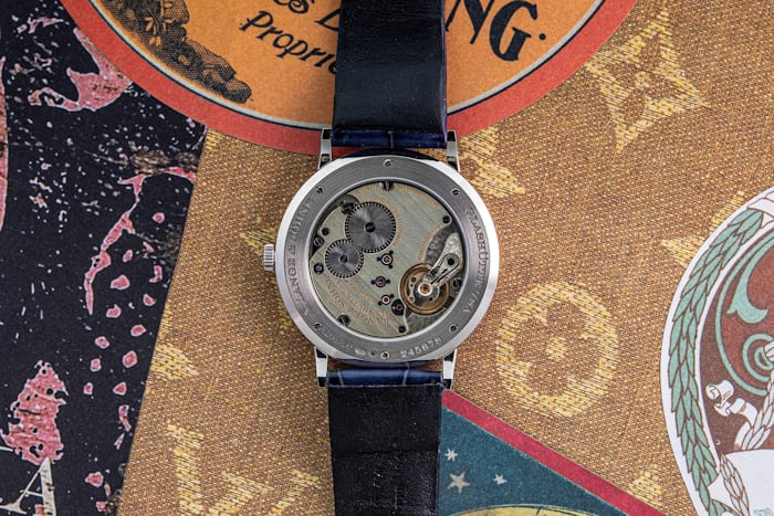 Caseback of a A. Lange & Sohne watch showing the visible movement on an ornate background