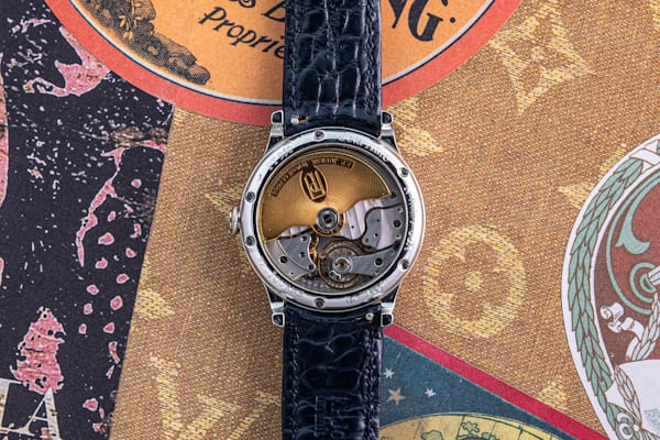 Caseback of an F.P. Journe watch showing the visible movement on an ornate background