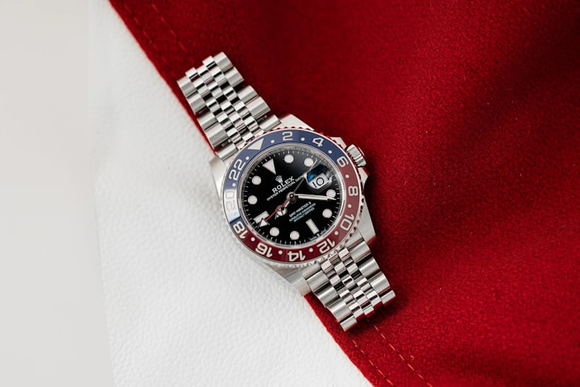 A Rolex GMT Pepsi watch rests on top of a red and white fabric