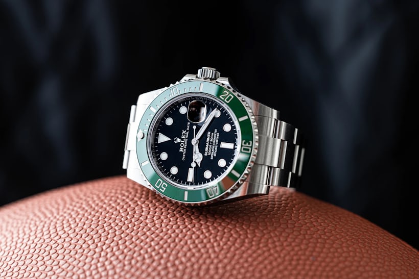 A Rolex GMT Hulk watch rests on its side on top of a textured surface