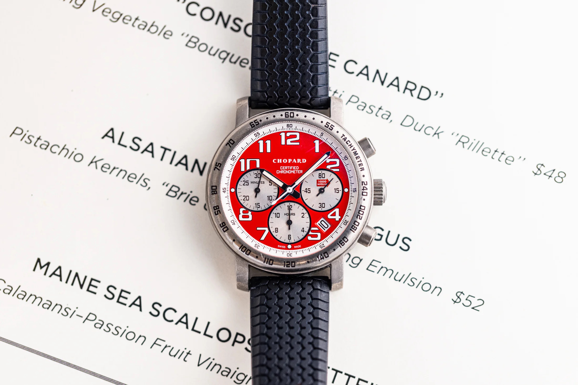 Red Chopard Chronometer placed on top of a dinner menu