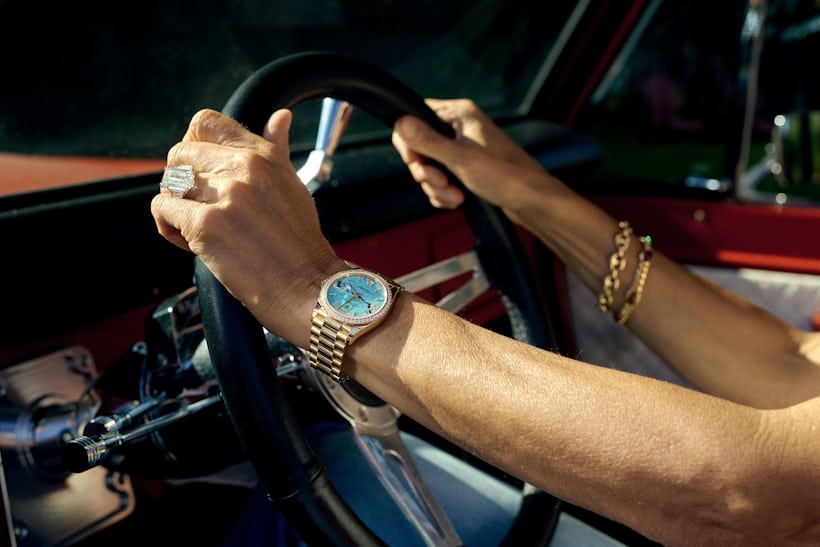 A woman wears a Rolex Day-Date in her car. 