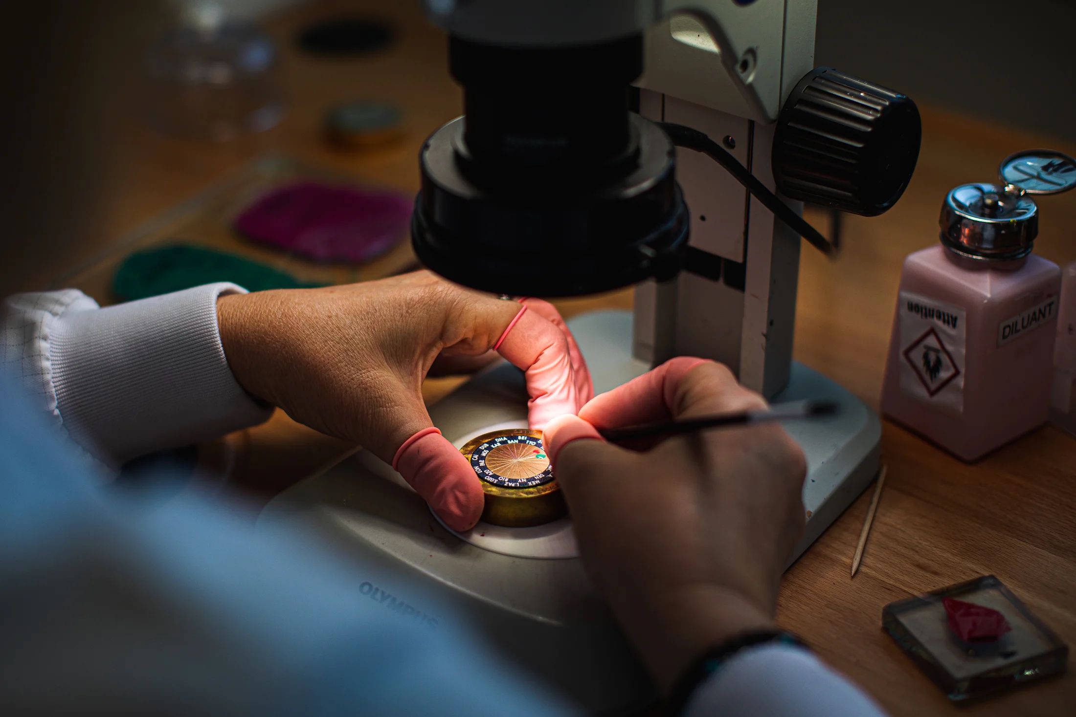 A watchmaker works diligently on hand-painting a watch dial