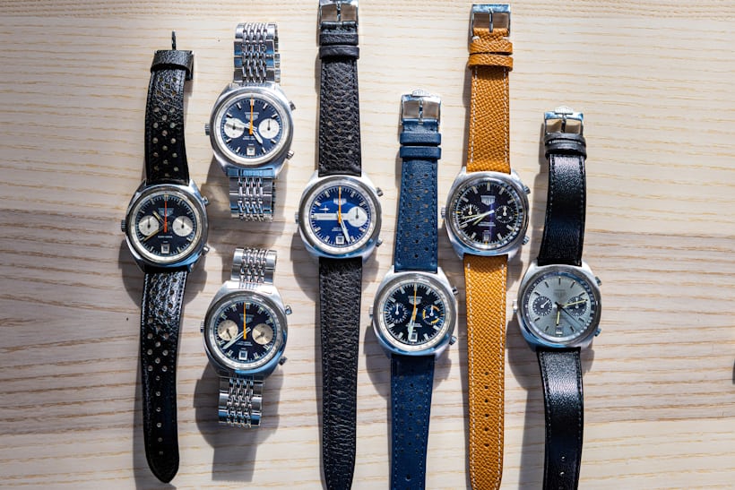 A group of carrera watches with c-shaped cases laid out on a wooden surface