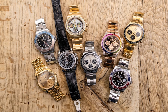 Collection of Rolex and Patek watches on a wooden surface