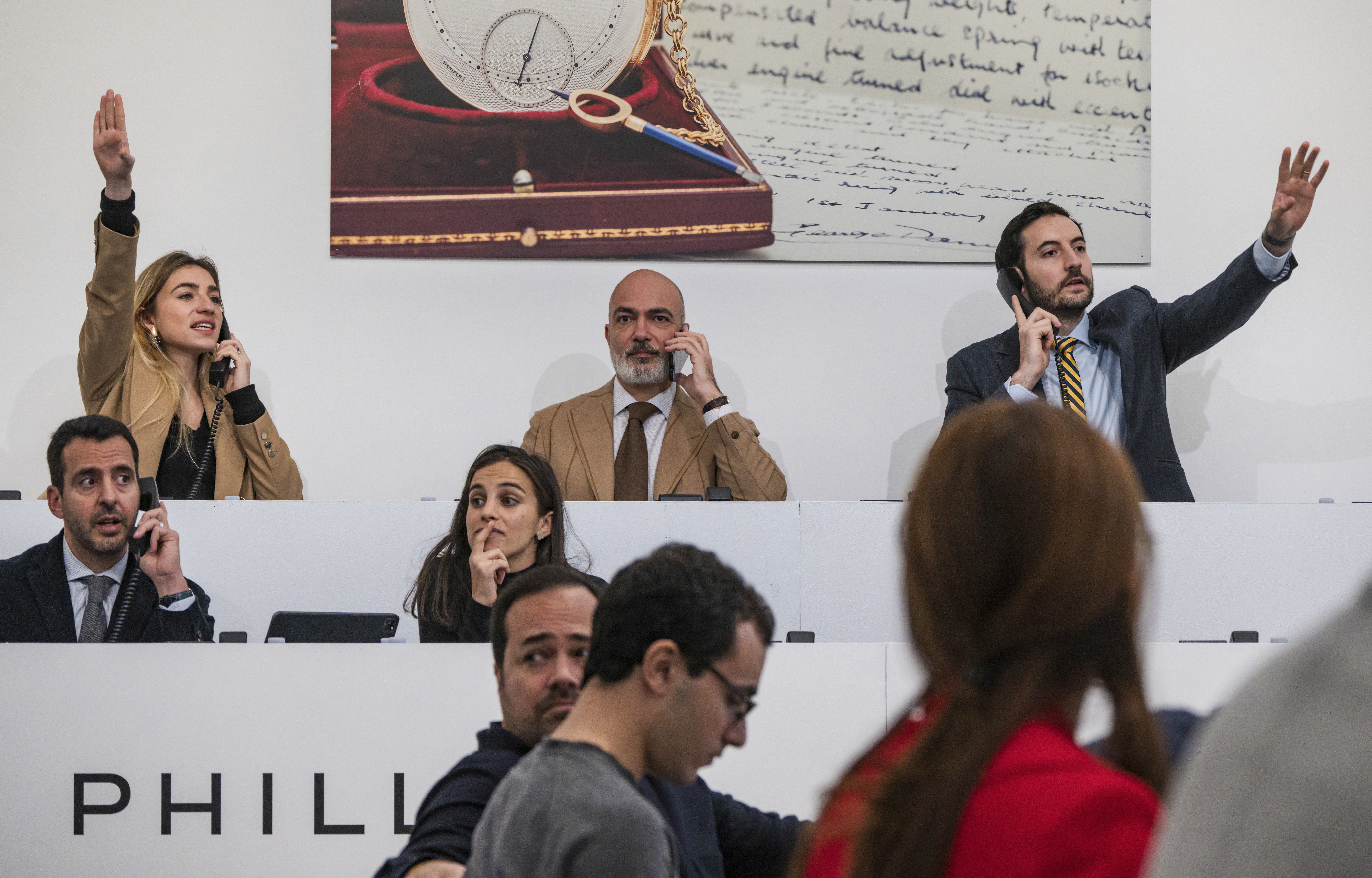 Auctioneers raise their hand at the rostrum. 