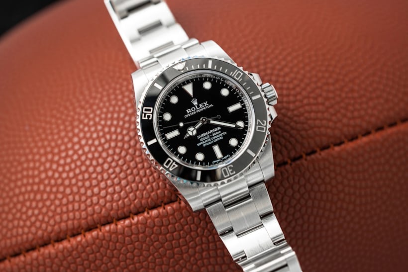 A Rolex Submariner watch with a black dial and black bezel rests on a textured background