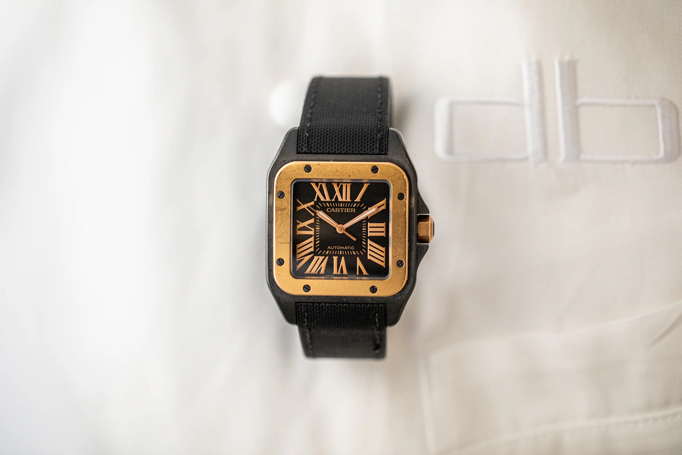 Cartier wristwatch on a white cloth background with the letters "db" embroidered