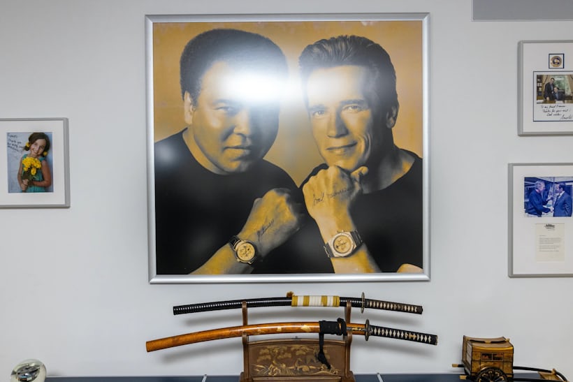 View of the wall of François' office showing two katanas and various photos on the wall, the largest one being a signed photo of Muhammed Ali (left) and Arnold Schwarzenegger (right) wearing ap watches