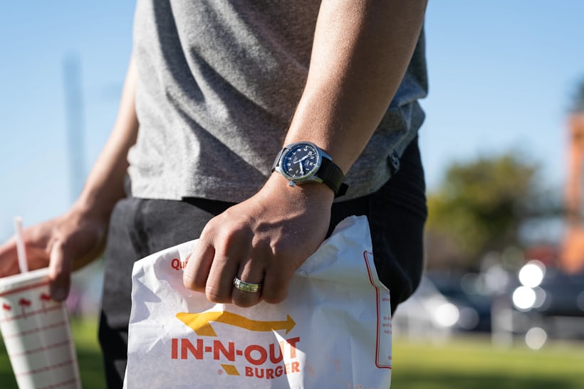 person wearing watch while holding fast food bag