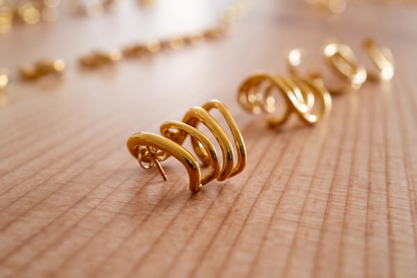Close up of a piece of curvy jewelry on a wooden tabletop with other out-of-focus jewelry in the background
