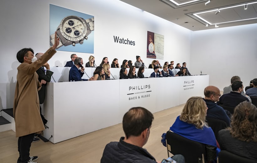 A man raises his hand while bidding on a watch at Phillips Auction House in New York
