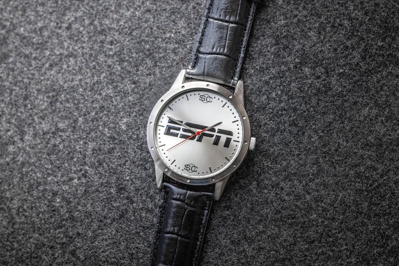 An ESPN special edition watch rests on top of a textured gray surface