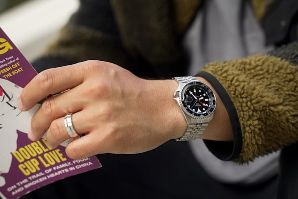 holding book with watch on wrist
