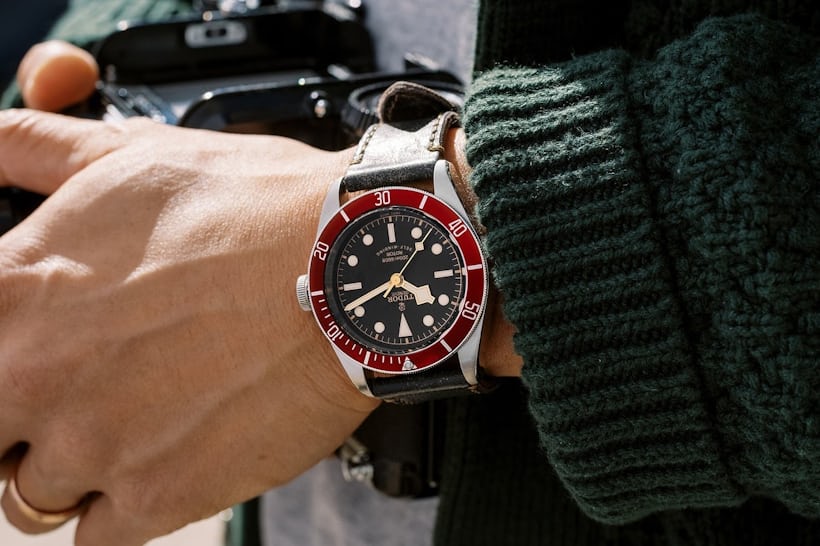 A Tudor Heritage Black Bay Red 79220R on the wrist of a man holding a camera.
