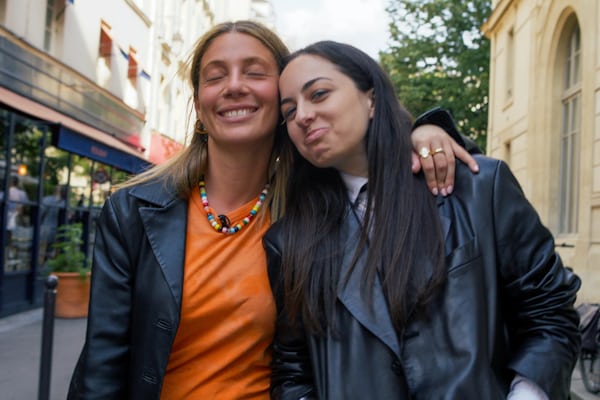 Malaika Crawford and Willa Bennett leaning on each other while walking through the streets of Paris, France
