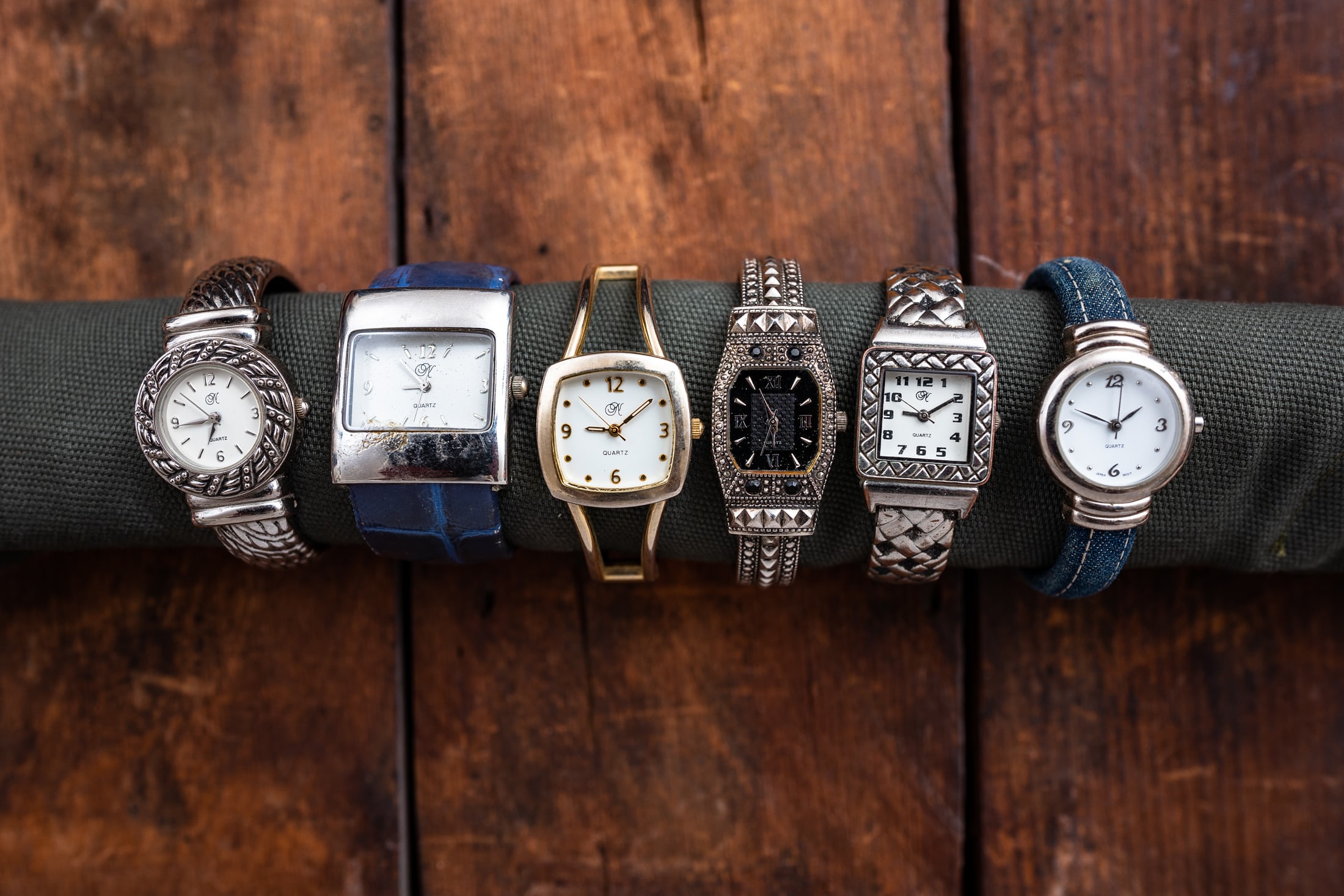 Several more cuff watches all aligned on a table. 