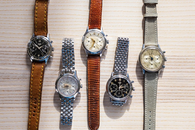 A group of Pre-Carrera watches laid out on a wooden surface