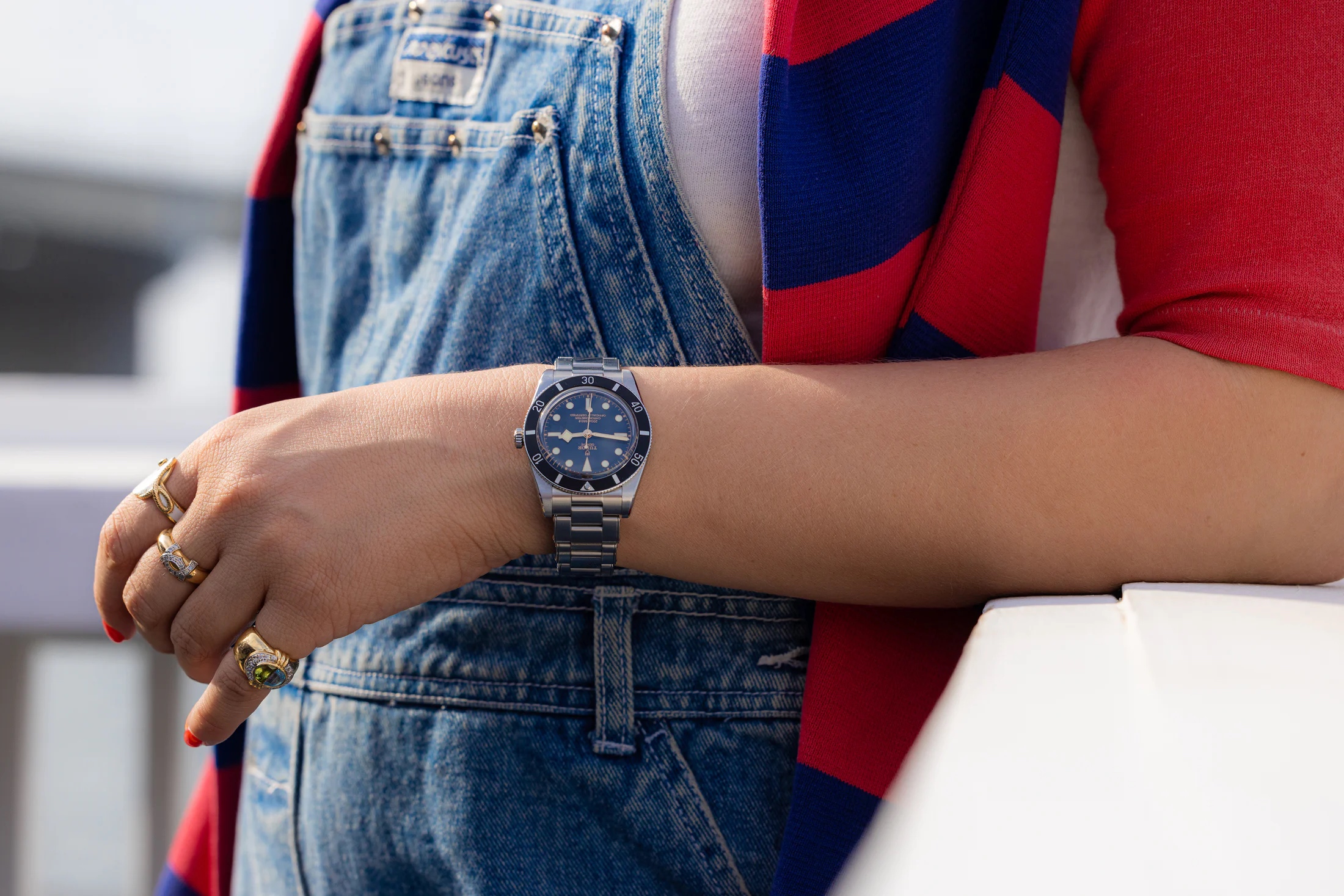 チューダー　ブラックベイ 54を腕につけ、バリアの端に寄りかかる女性