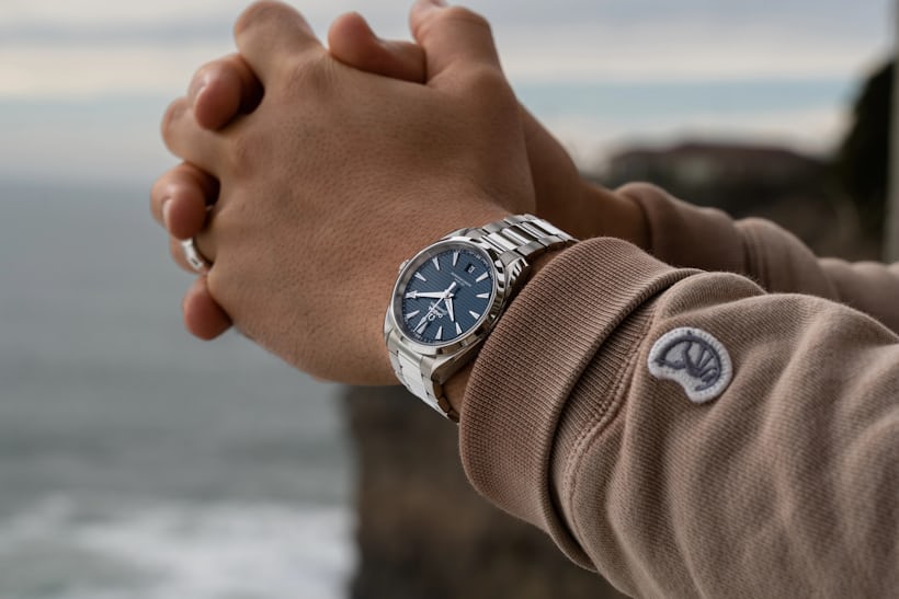 watch on wrist with ocean and cliff in background