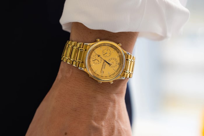Close up of the wrist of a man wearing a gold Seiko World Timer watch