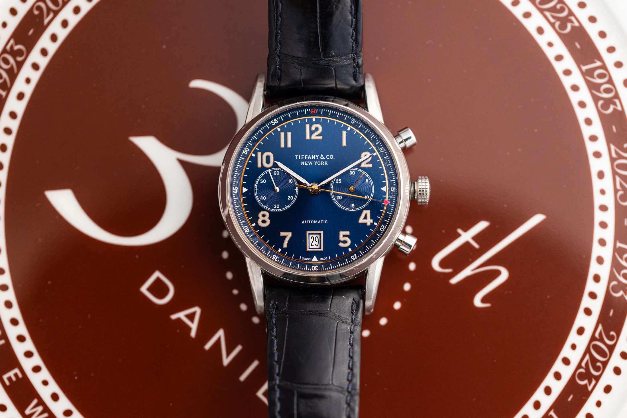 Tiffany & Co. Chronograph with blue dial on a red background with stylized text