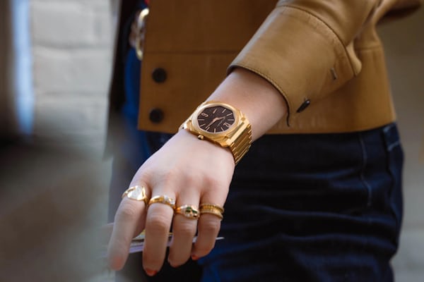 A woman flips the page of a book while wearing multiple rings and the bulgari octo finissmo watch on her wrist