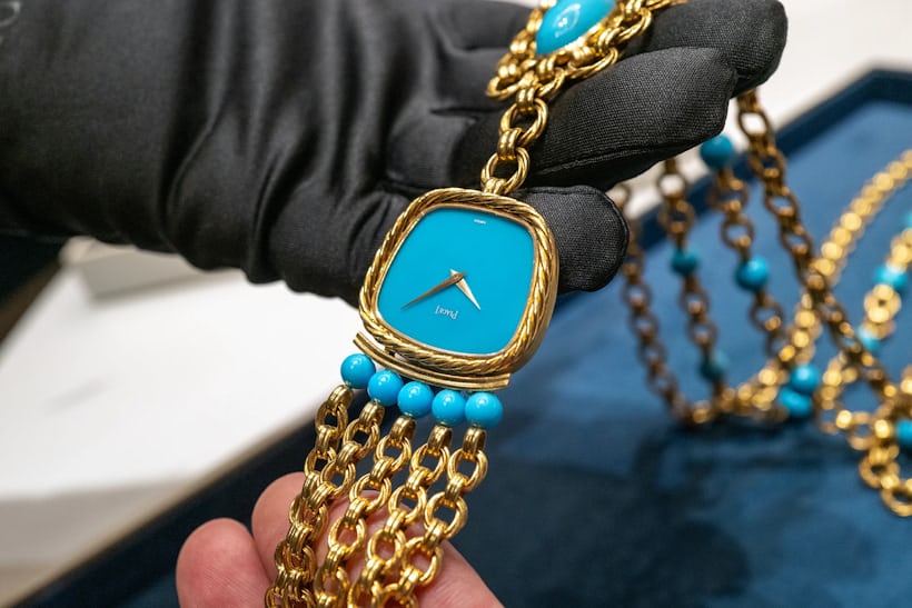 Close up of a Piaget necklace featuring a watch component with an opaque blue dial