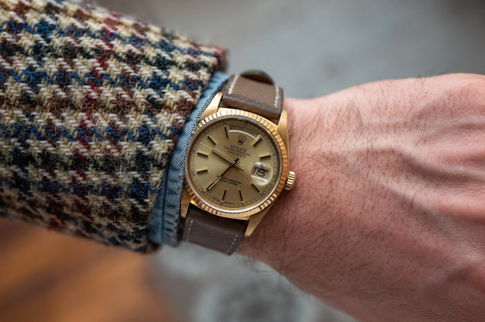 A yellow-gold Rolex Day-Date on a man's wrist,