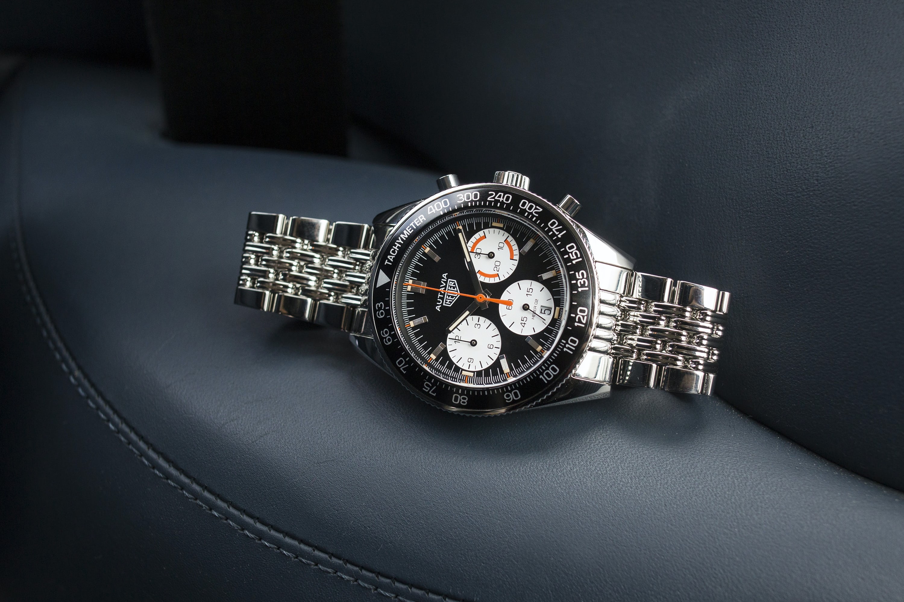 The TAG Heuer Autavia Calibre Heuer 02 For HODINKEE leaning on its side in the front seat of a car.